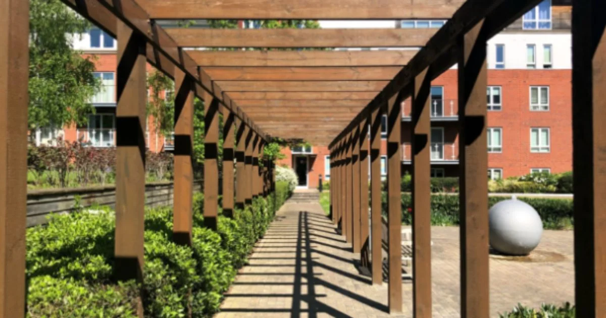 Wooden pergola breezeway in a landscaped courtyard.